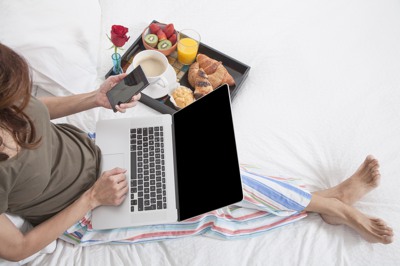 Woman in bed with breakfast and laptop