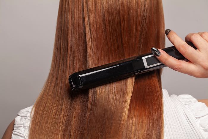 Woman using hair straighteners